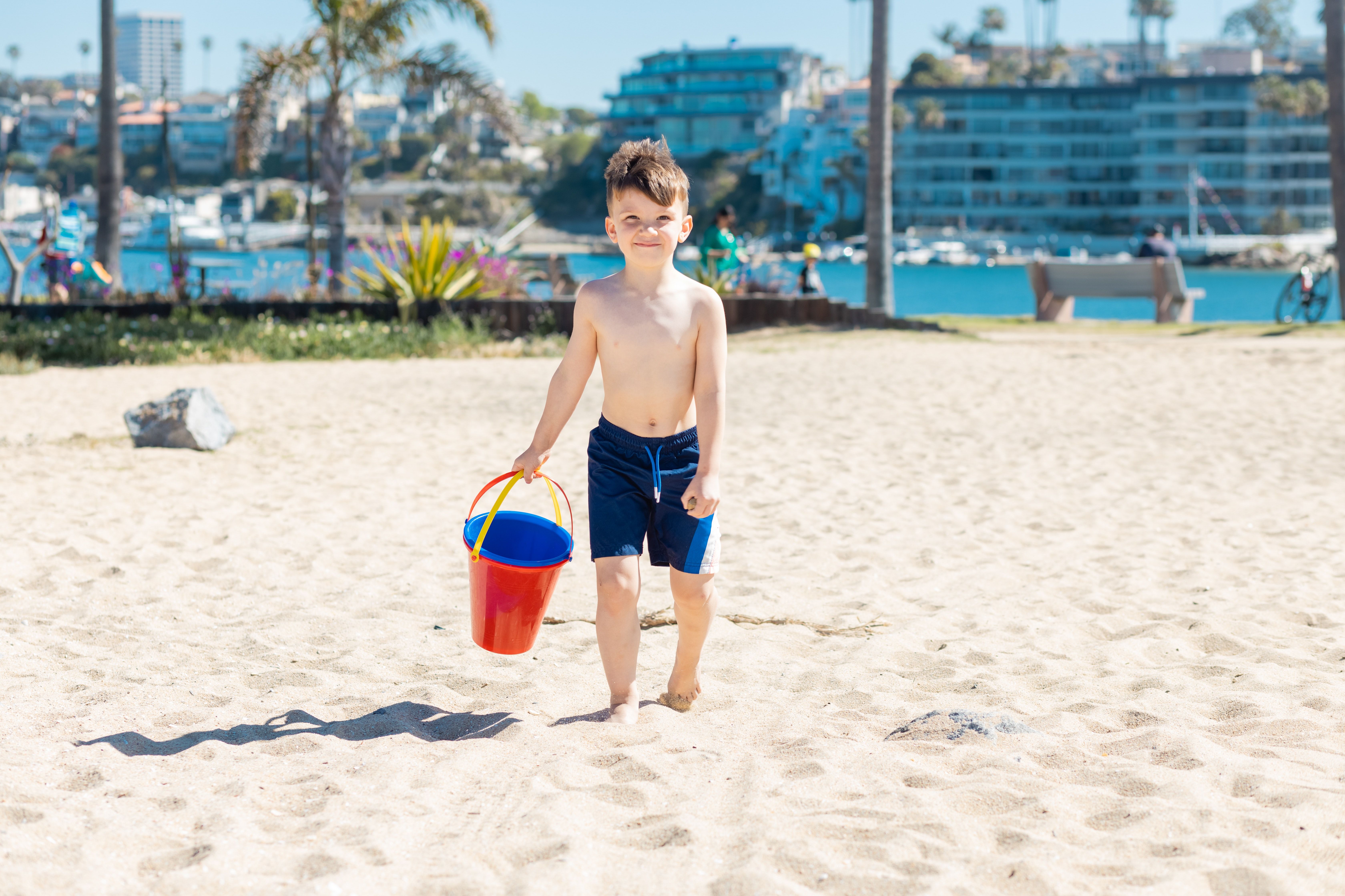 Vaikas su kibirėliu ant smėlio